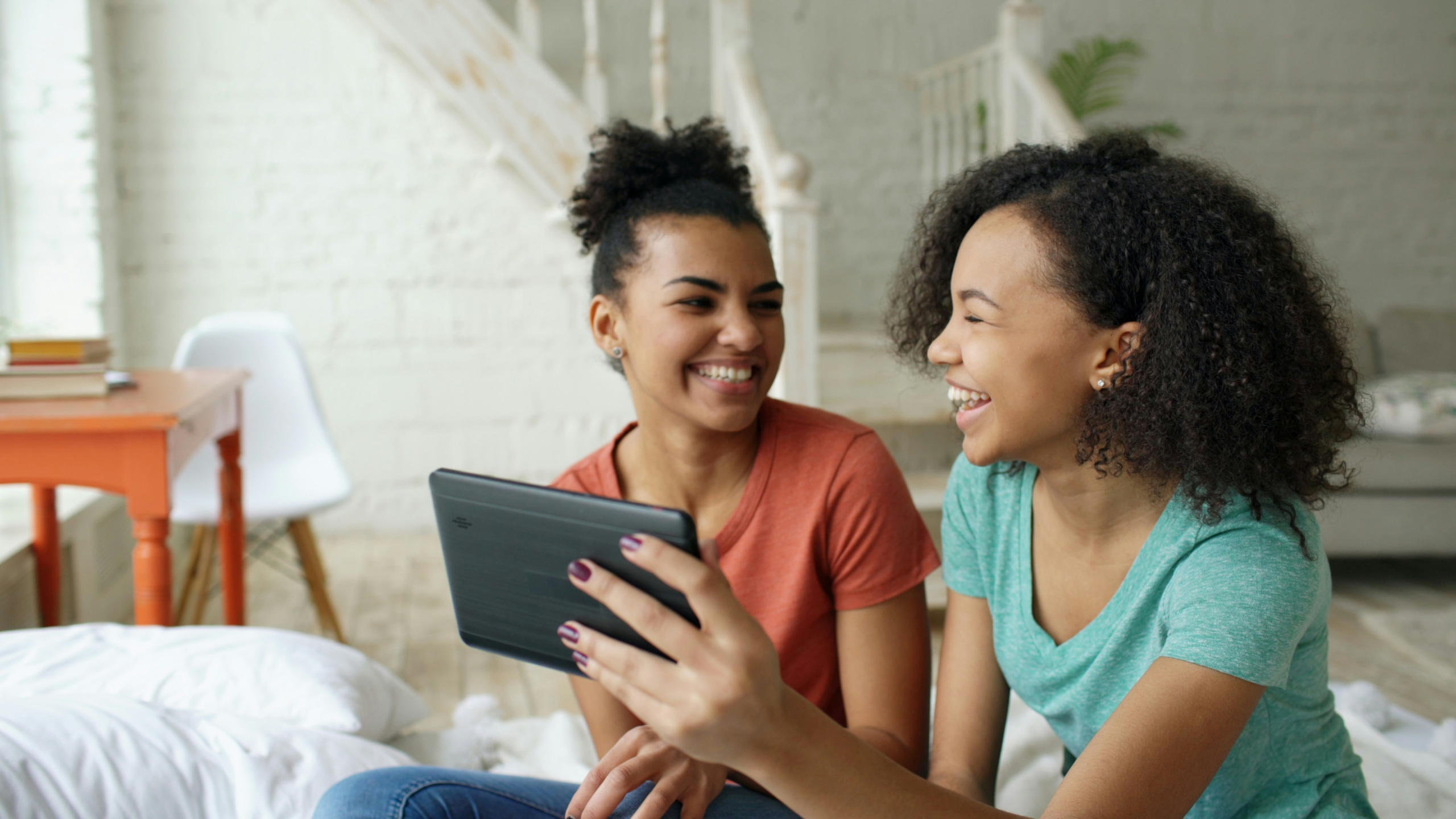 Two teenage girls smiling while using a smartphone together.